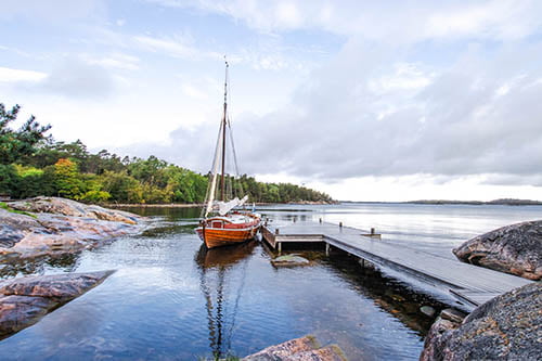 A fancy wooden sailing boat docked on a pier in the archipelago
