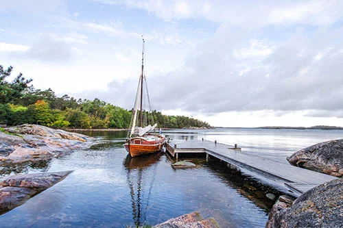 A fancy wooden sailing boat docked on a pier in the archipelago
