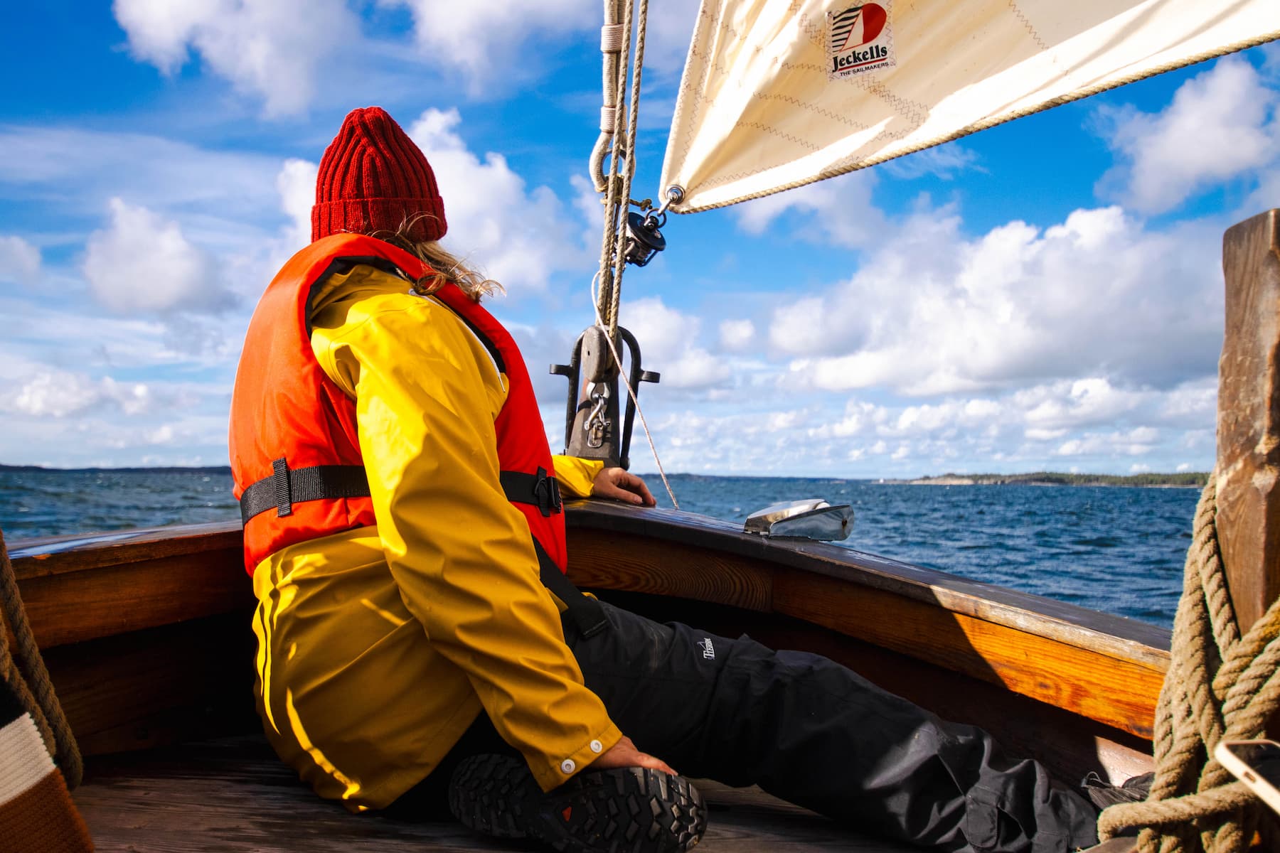 A person looking out towards the sea from the bow of a sailing boat.