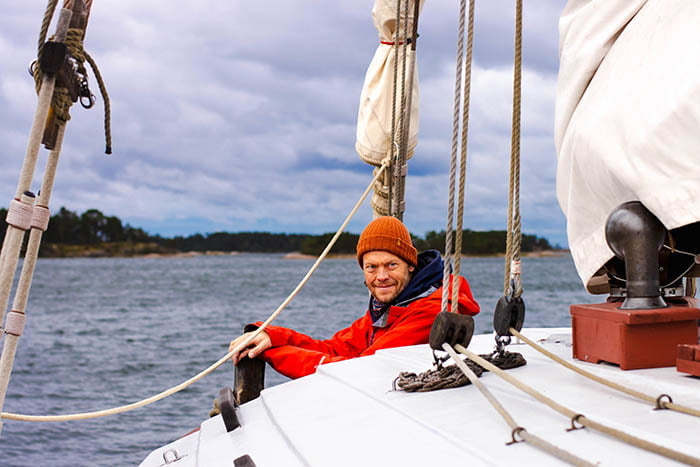 A man in a red jacket on a sailboat.