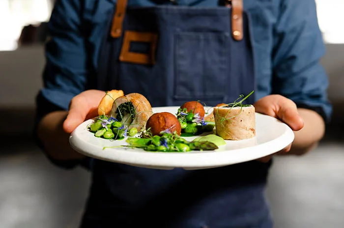 A chef is holding a plate of food.