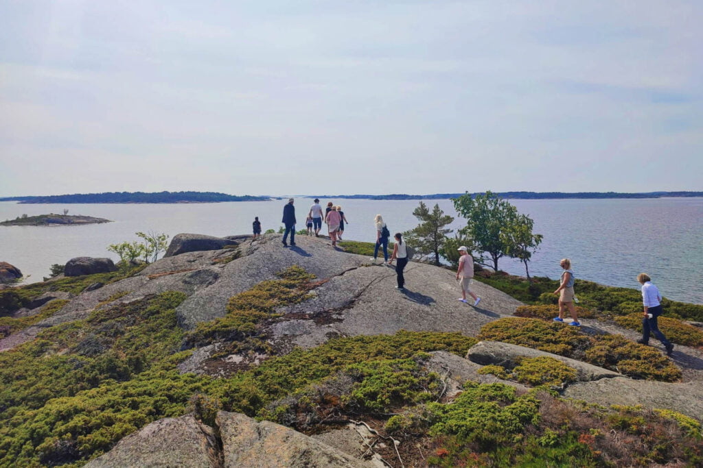 A group of people standing on top of rocks near the water.