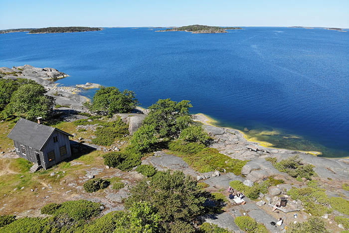 An aerial view of a small cottage on a rocky island.